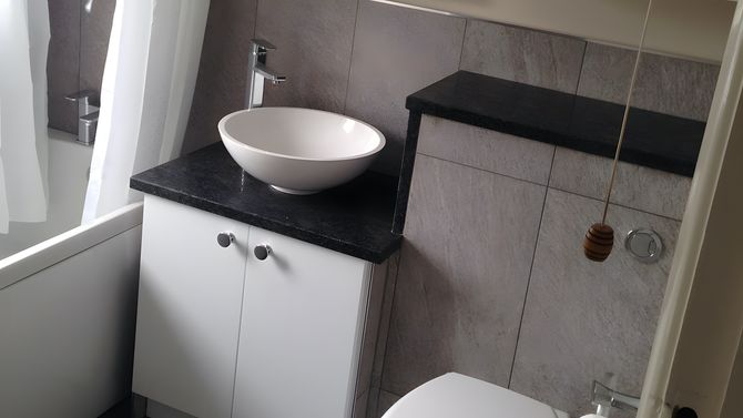 A newly fitting bathroom suite, with tiled boxing around a vanity unit.